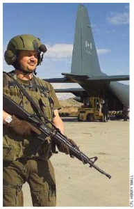 Canadian military policeman Cpl. Eric Belanger stands guard with a C7A1 assault rifle while humanitarian aid is unloaded from a CC-130 Hercules in Afghanistan.