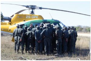 Trainee rangers crowd around a Kruger Park helicopter while the pilot instructs them about how to load and unload. 