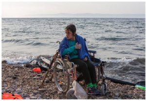 Nojeen, a16-year-old Syrian refugee, who uses a wheelchair due to a balance problem, waits to be lifted to the road. She and her older sister landed on the Greek island of Lesbos after crossing from Turkey, in hopes of finding better medical care. Greek authorities are looking after her. (Photo: © UNHCR/Ivor Prickett)