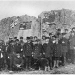 Captain Bernier (with the young muskox) claims Canada's jurisdiction at Parry's Rock by laying a plaque in July 1909.