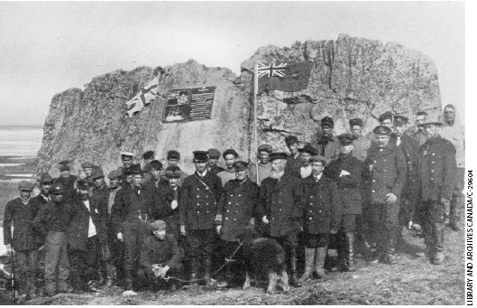 Captain Bernier (with the young muskox) claims Canada’s jurisdiction at Parry’s Rock by laying a plaque in July 1909.