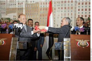 Ali Abdullah Saleh, right, hands Abed Rabbo Mansour Hadi the flag of Yemen.  