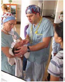 Nurse Heather Posno holds a baby while anesthetist Clayton Reichert looks on during a ORC mission to Cambodia earlier this year. 