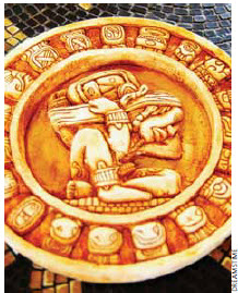 A carved stone Mayan calendar on tile background. 