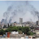 Smoke drifts into the sky from buildings and houses hit by shelling in Homs, Syria, in June.