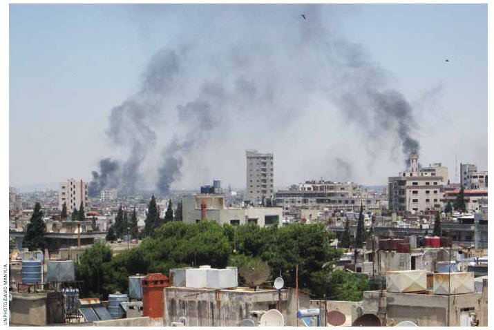 Smoke drifts into the sky from buildings and houses hit by shelling in Homs, Syria, in June. 