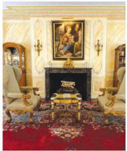 The main receiving room has a fireplace, elaborately painted crown mouldings and gold-accented furnishings. 