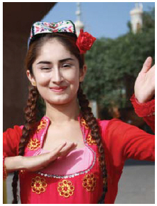 A dancer in brightly coloured traditional dress and handembroidered Uyghur flower hat performs for tourists visiting Kashgar. (Photo: Ülle Baum)