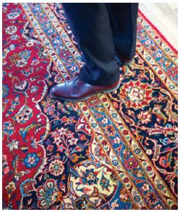 Khan stands on one of the intricately designed carpets, handmade by Pakistani families. (Photo: Ashley Fraser)