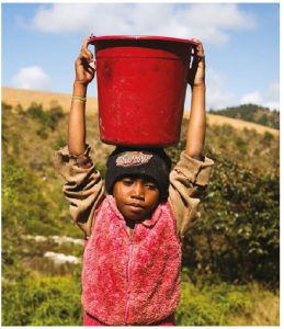 Eight-year-old Neny carries a bucket full of dirty water on her head on her way back home from her family's only water source in Tsarafangitra village, Belavabary commune, Madagascar. (Photo: WaterAid, Ernest Randriarimalala)