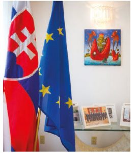 Two tables of souvenir photos, including one of the couple with Prime Minister Justin Trudeau, grace the living room. One of the tables sits next to the Slovak and EU flags. (Photo: Ashley Fraser)