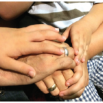 A journalist, his wife, and his three children clasp hands. Now settled in a one-bedroom Air BnB in Athens, they are trying to put their lives back together while worrying about family members they had to leave behind in Turkey. (Photo: Jennifer Campbell)