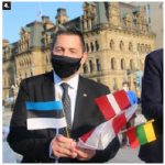 MP Jamie Schmale, chairman of the Canada-Nordic-Baltic Parliamentary Friendship Group, holds the flags of Estonia, Latvia and Lithuania. He spoke at the Baltic event. (Photo: Ülle Baum)