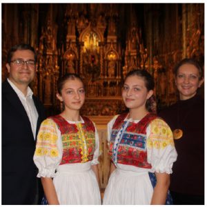 Sabina Koziakova, centre left, and Terezia Koziakova, centre right, daughters of Slovakian Ambassador Vit Koziak, far left, performed Jasna hviezdicka, a Slovakian Christmas carol. The girls are wearing handmade folk costumes and their mother, Terezia, is at right. (Photo: Sabina Koziakova, centre left, and Terezia Koziakova, centre right, daughters of Slovakian Ambassador Vit Koziak, far left, performed Jasna hviezdicka, a Slovakian Christmas carol. The girls are wearing handmade folk costumes and their mother, Terezia, is at right. (Photo: Ülle Baum)