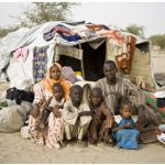 A refugee family — who fled Boko Haram attacks in Nigeria — sit in front of their shelter at the Sayam Forage Refugee Camp in Niger. (Photo: © UNHCR/Hélène Caux)