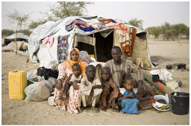 A refugee family — who fled Boko Haram attacks in Nigeria — sit in front of their shelter at the Sayam Forage Refugee Camp in Niger. (Photo: © UNHCR/Hélène Caux)