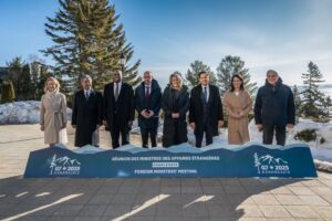 Group photo of G7 foreign ministers in Kananaskis standing behind a summit sign, symbolizing international cooperation.